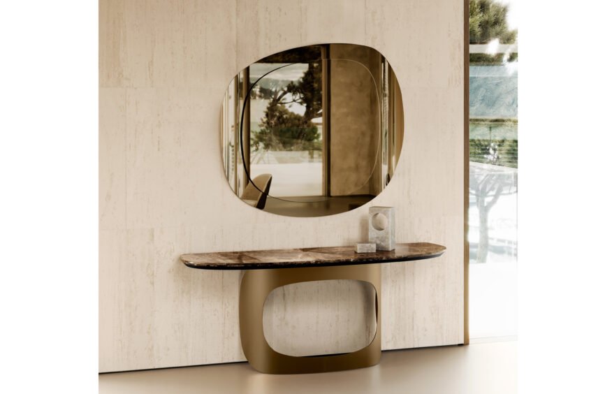 Dans un hall d'entrée contemporain, le miroir EMILY au design ovale abstrait est monté sur un mur texturé beige. Sous le miroir se trouve une élégante console incurvée avec un plateau en marbre et une base dorée sculpturale. Un petit objet décoratif orne la table. Meubles Barret Bordeaux